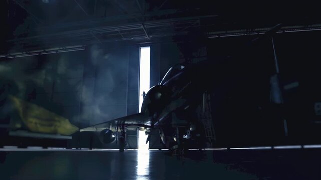 Cinematic View of a Military Fighter Jet Silhouette Inside a Darkened Aircraft Hangar - 4K