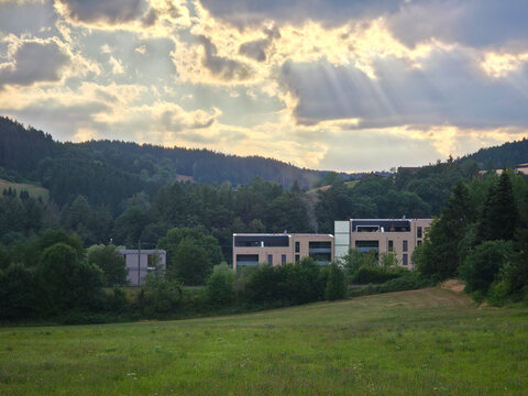 germany, newly built houses in elzach glowing beneath dramatic sunset clouds creating vibrant summer evening atmosphere in beautiful black forest village