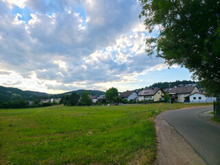 Fototapeta premium germany, scenic road leading into elzach black forest village surrounded by magical summer nature beneath glowing sunset sky and peaceful countryside