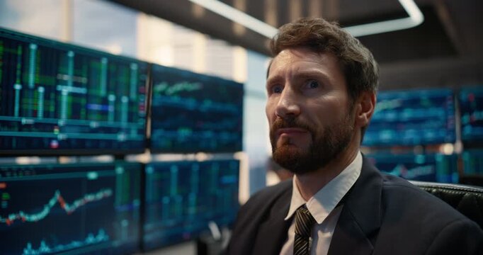 Thoughtful Male Stockbroker at an Asset Management Firm, Weighing Trading Strategy Against Multiple Screens While Shaping Corporate Decisions on Capital Growth and Banking Success. Camera Moving