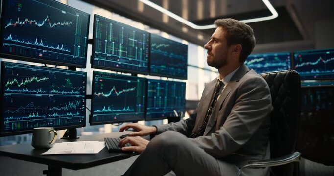 Professional Male Stockbroker Seated at Trading Desk Monitors Stock Exchange Data, Financial Charts and Market Trends Across Computer Screens, Evaluating Investment Capital Growth