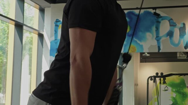 Man training triceps using cable pushdown machine in gym