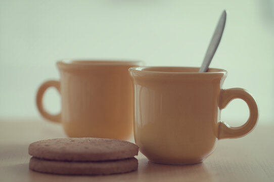Close-up of Two mugs of tea and biscuits on a table