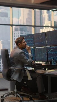 Vertical Screen. Portrait of Contemplative Male Investor Reviews Stock Exchange Data and Financial Charts at Desk, Pondering Trading Decisions and Capital Growth Strategy in Brokerage Firm Office.