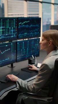 Vertical Screen. Focused Female Broker Analyzes Stock Market Data and Financial Charts at Desk, Typing on Computer While Monitoring Investment Portfolio and Capital Growth Trends in Office.