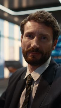 Vertical Shot of a Confident Businessman Trader Working on Stock Market Strategy in a Modern Asset Management Firm. Broker Turns and Lookis at Camera.