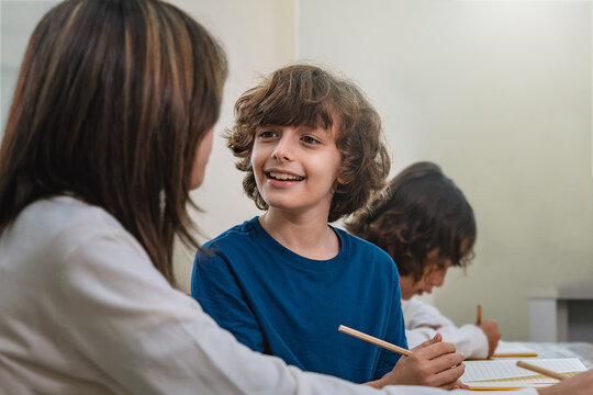 Smiling boy pupil discussing with young girl classmate during handwriting lesson, highlighting positive communication in classroom, capturing warmth interaction and emotional connection