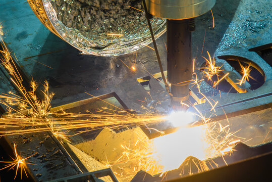 High-power laser cut machine operation cutting a high thickness metal plate with dramatic sparkling light.