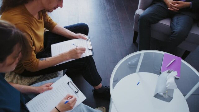 Young couple completing a questionnaire during a counseling session with a male psychologist