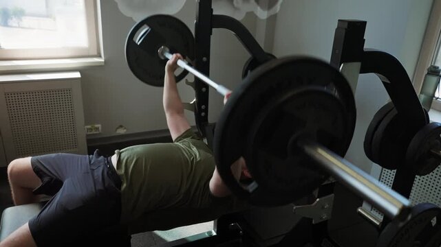 Man bench pressing heavy barbell weights in gym