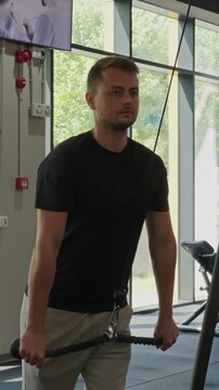 Man exercising using cable machine for triceps pushdown