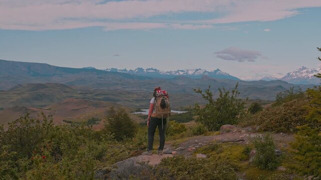 Back view of female hiker with backpack enjoy stunning lush scenery with mountains and lakes in the distance, W-Trek, Torres del Paine, Patagonia, Chile