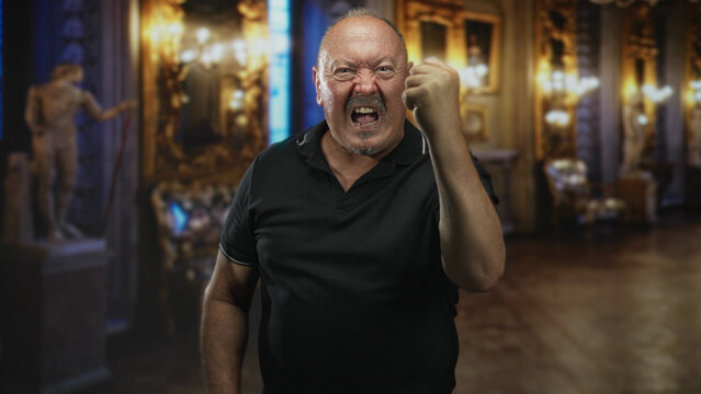 Man clenches fist, grimacing with teeth bared and raised knuckles, standing before gilt frames and marble statues in ornate building; anger defiance.