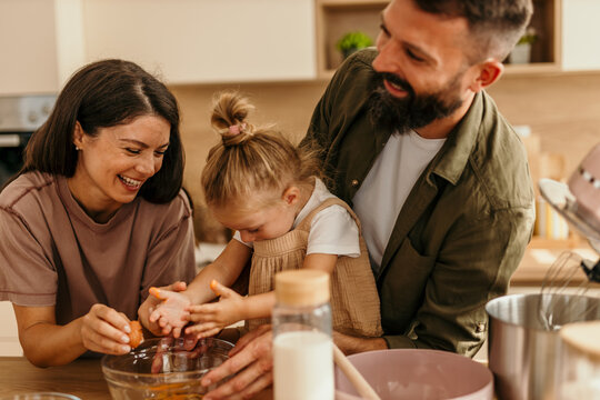 Happy family baking together, breaking eggs in kitchen
