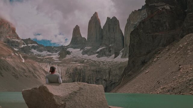 Woman sitting on a rock taking in the picturesque granite towers of Torres del Paine with parallax movement, Patagonia, Chile 