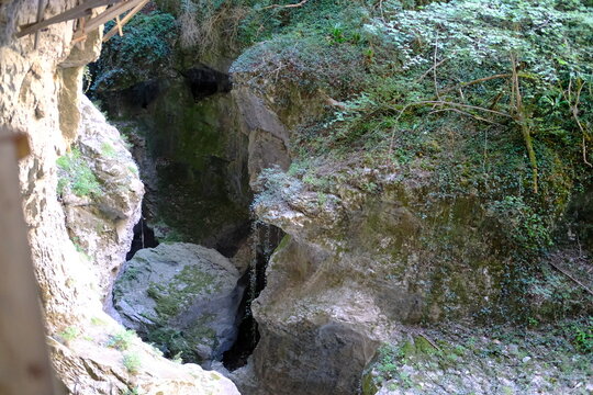 Narrow rocky canyon with mossy cliffs and dark cave entrance in nature