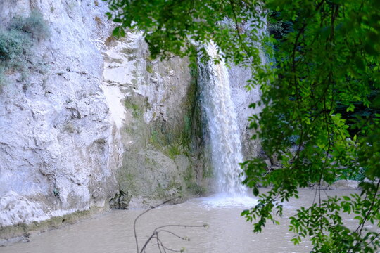 Beautiful waterfall cascading down white rock cliff surrounded by green foliage