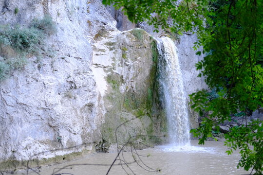 Beautiful waterfall cascading down white rock cliff surrounded by green foliage