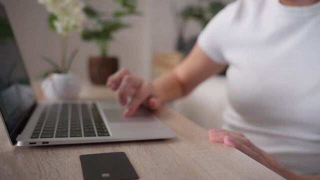 Woman browsing online stores on laptop with bank card on table. Comparing prices, searching best deals, seasonal discounts and convenient ecommerce shopping from home.