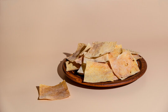 Square Armenian lavash chips arranged on a round clay plate space for text.