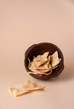 Armenian lavash chips in a clay bowl on a beige background; space for text.