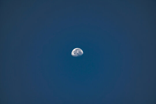 Detailed gibbous moon in clear blue evening sky.
