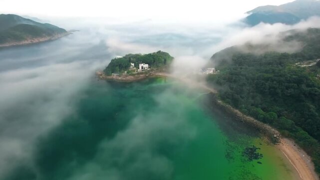The beauty of a tropical coastal landscape shrouded in thick mist and low-hanging clouds moving dramatically. 