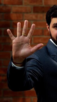 Showing numbers using fingers with confident expression, Indian Asian bearded ceo businessman in formal corporate attire demonstrating finger counting while standing in cozy office against brick wall