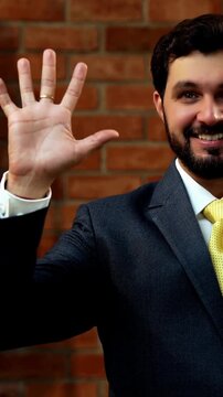 Showing numbers using fingers with confident expression, Indian Asian bearded ceo businessman in formal corporate attire demonstrating finger counting while standing in cozy office against brick wall