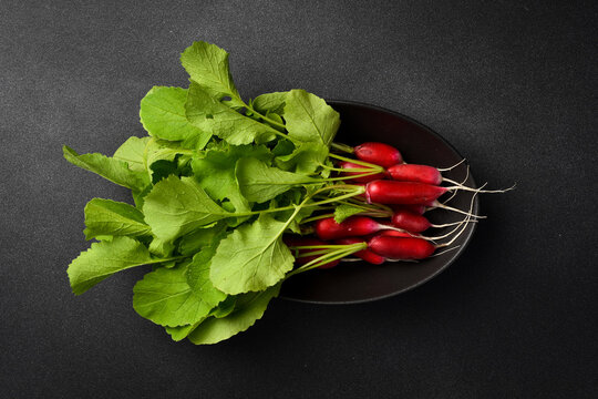 Fresh organic red radish on a black stone plate. On a dark stone background.