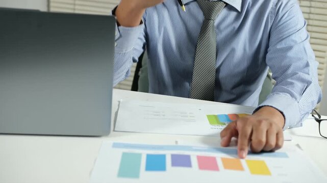 Concept Business working on a report or questionnaire writing notes with a pen and readind financial report analyzing statistics pointing at pie chart working at desk.
