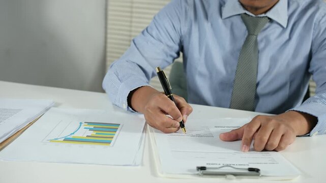 A businessman signs and submits contract documents on his desk.