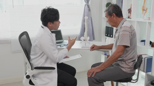 A professional male doctor consults with and explains the treatment plan to an elderly patient, using a spinal structure model to discuss the treatment.