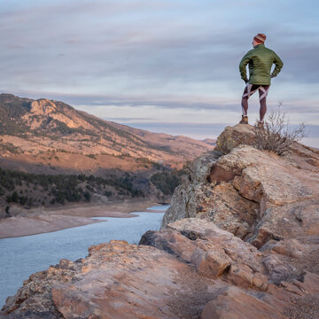 male hiker on a cliff overlooking Horsetooth Reservoir, popular recreation destination for boating, hiking and biking in northern Colorado, fall scenery at sunrise