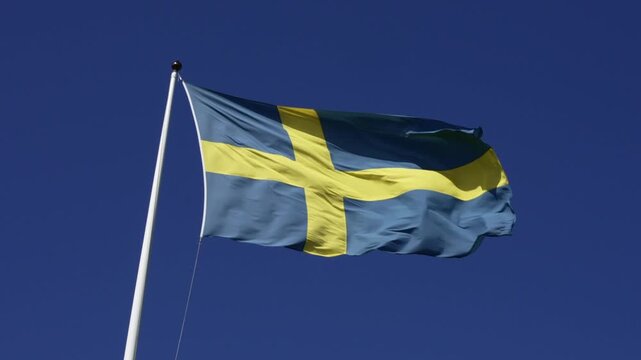 Swedish flag in strong wind against dark blue sky