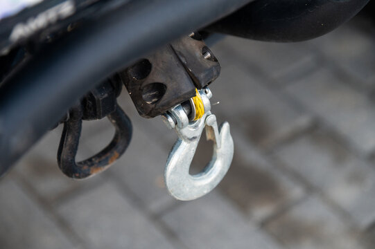 Close-up of metal tow hook attached to vehicle hitch on paved surface