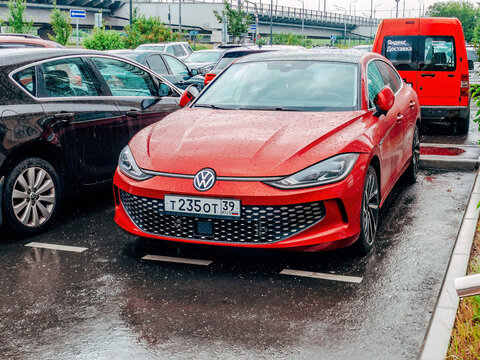 city parking lot on a rainy day and bright red car Volkswagen Lamando