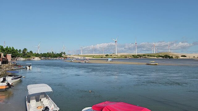 Beautiful panoramic view of Munda&uacute; Beach featuring leisure boats on clear water and massive wind turbines.