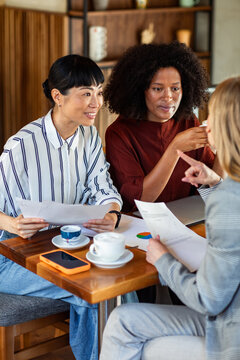 Three businesswomen discussing charts at cafe
