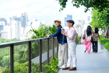 Couple Asian lover of lgbt stand together in the walkway in public park and one man hold camera to take a photo and they look happiness to relax together in big city.