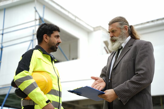 Construction Engineer Discussing Building Project Issues with Senior Client at Construction Site