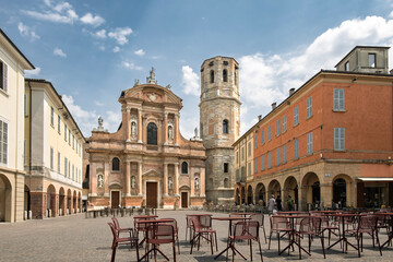 Fototapeta premium Piazza San Prospero in Reggio Emilia Italy, featuring the baroque facade of the Basilica of San Prospero and its famous octagonal bell tower. The square is depicted with outdoor cafe tables and chairs