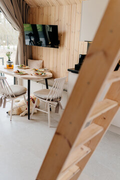 Vertical pet friendly tiny cabin with dog resting beneath prepared dining table near loft ladder