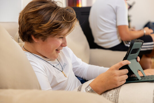 two pre teen boys gaming at home on a tablet