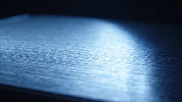 Close up of brushed metal surface with blue light reflection, macro view of textured metallic material with copy space for text, dark moody industrial concept