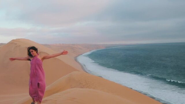 Woman with pink dress exploring Sandwich Harbour sand dunes