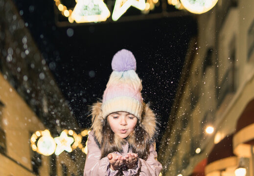 Child blowing snow in winter holiday lights