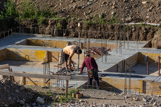 Construction Workers Pouring Concrete at Building Site During Foundation Work