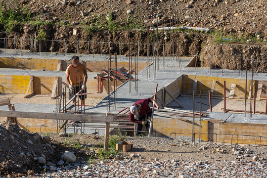 Construction Workers Pouring Concrete at Building Site During Foundation Work
