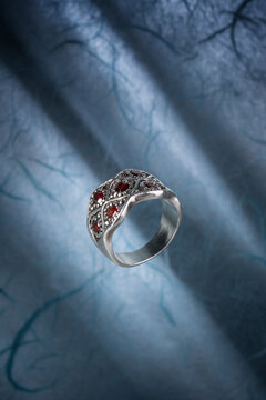 Boho style band ring is crafted from 925 sterling silver and features natural red garnet stones, photographed on light blue parchment
